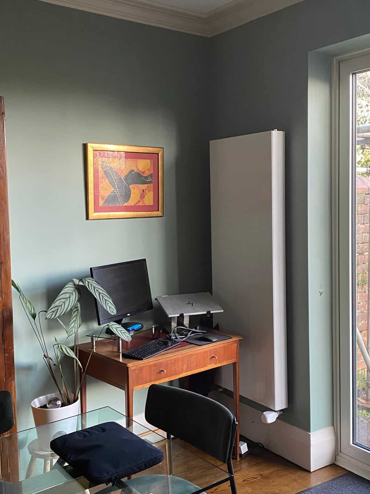 New vertical radiator installed in the dining room as part of the heat pump retrofit, providing efficient heating while complementing the renovated interior.