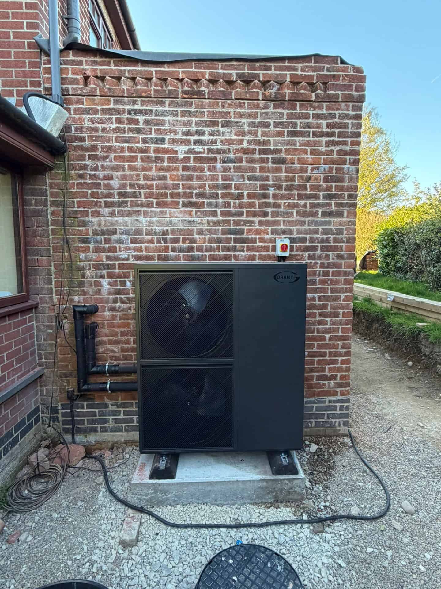 Grant Aerona 15.5kW R290 air source heat pump installed outside a detached off-gas home in Ashbourne, Derbyshire.