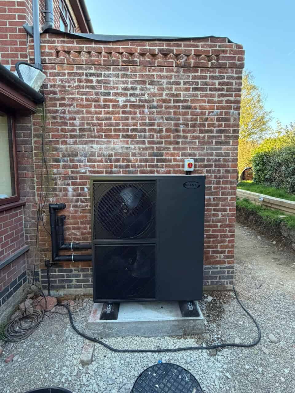 Grant Aerona 15.5kW R290 air source heat pump installed outside a detached off-gas home in Ashbourne, Derbyshire.