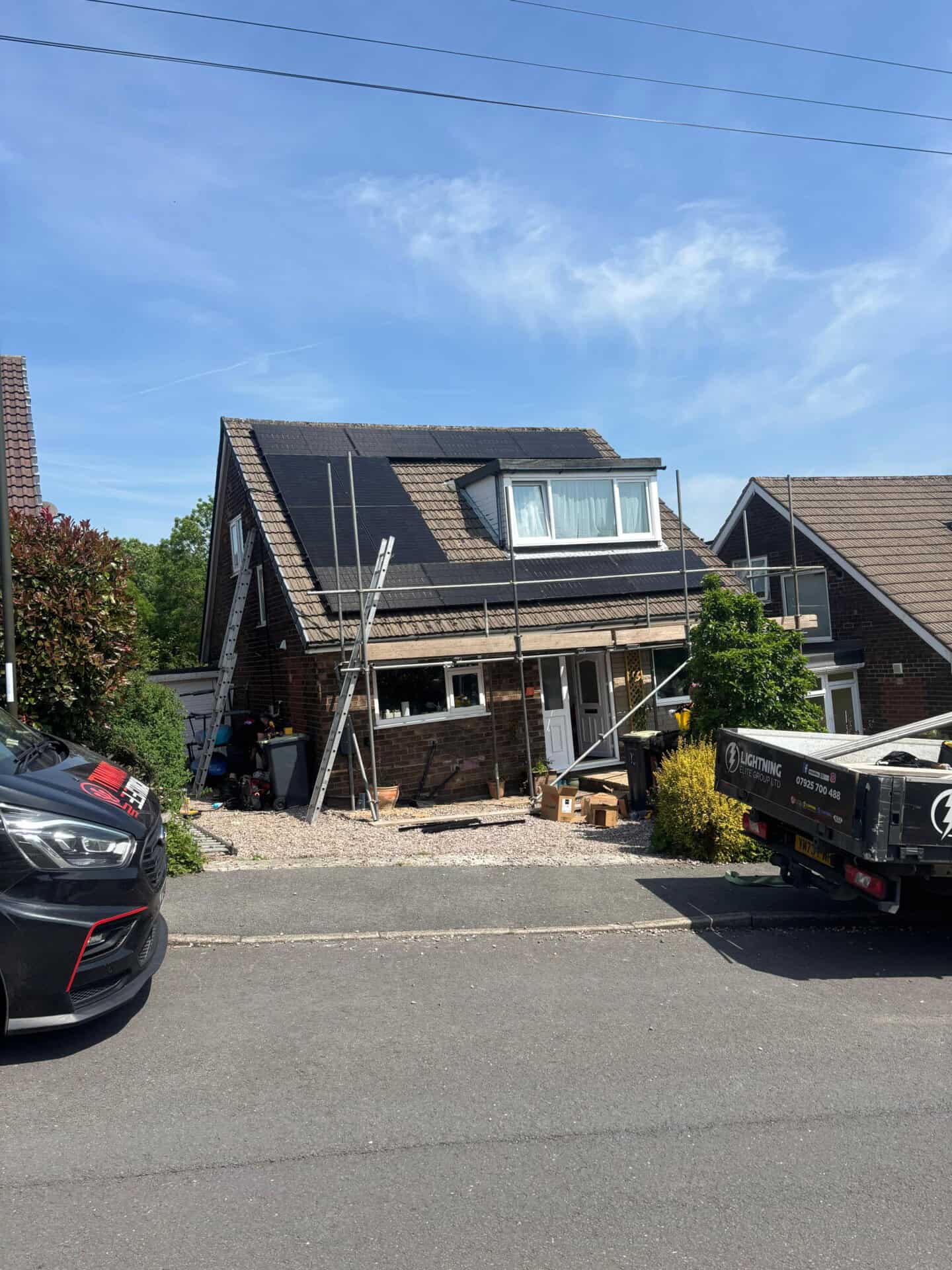Nearly completed solar panel installation on a detached home with dormer roof.