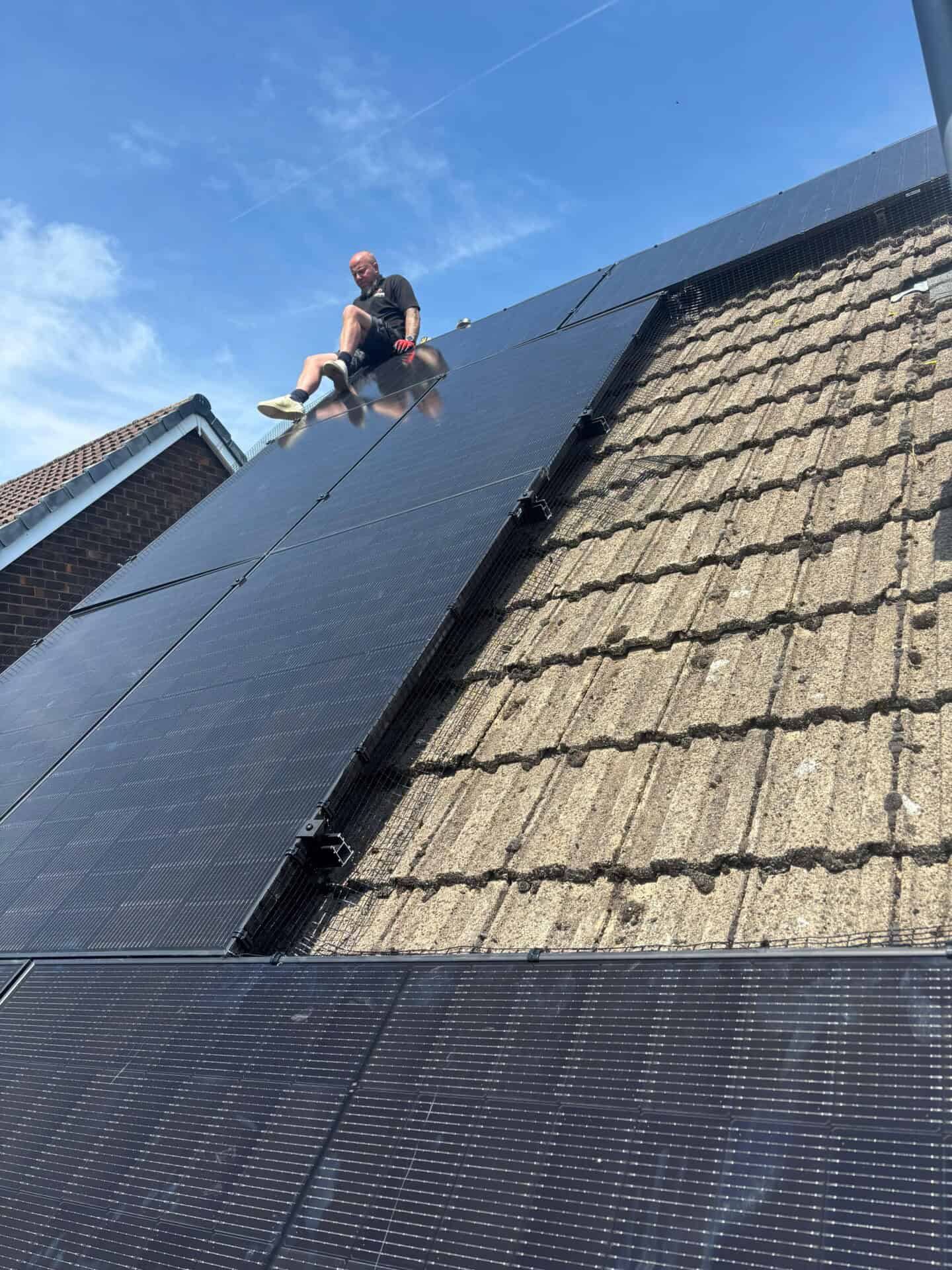 Solar panels being installed on a tiled roof around a dormer window.