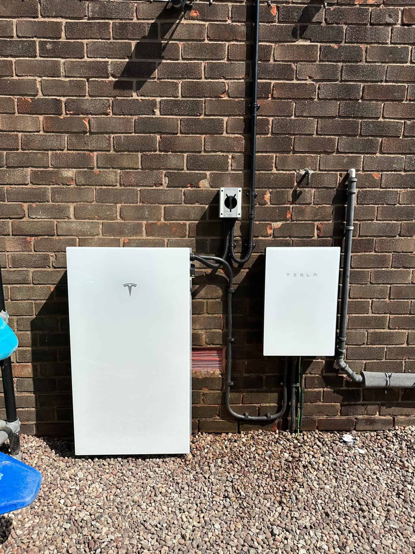 Tesla Powerwall 3 battery and Tesla Gateway installed on an exterior wall.