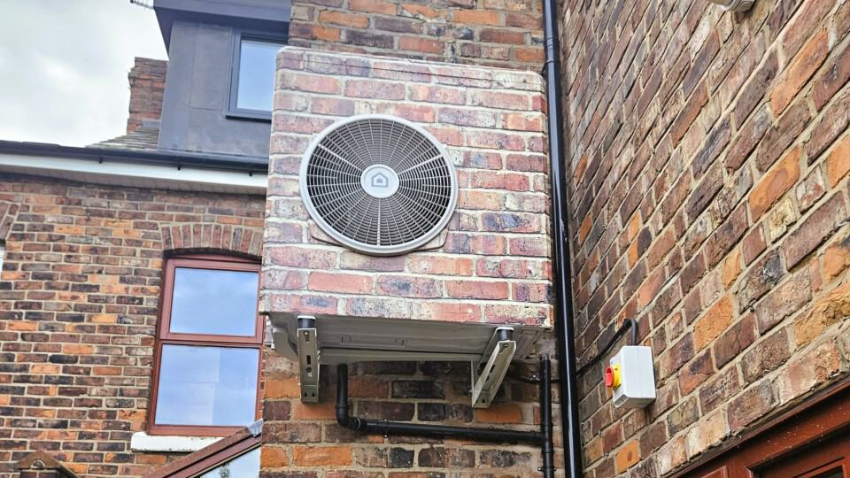 Ariston air source heat pump mounted on the side of a Victorian brick-built terraced house, wrapped in matching brick vinyl to blend with the exterior.